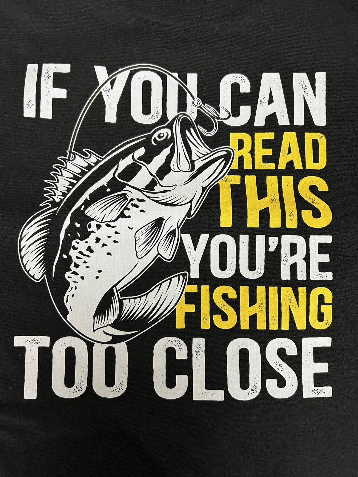 Close-up of the Fishing Too Close print on a black t-shirt