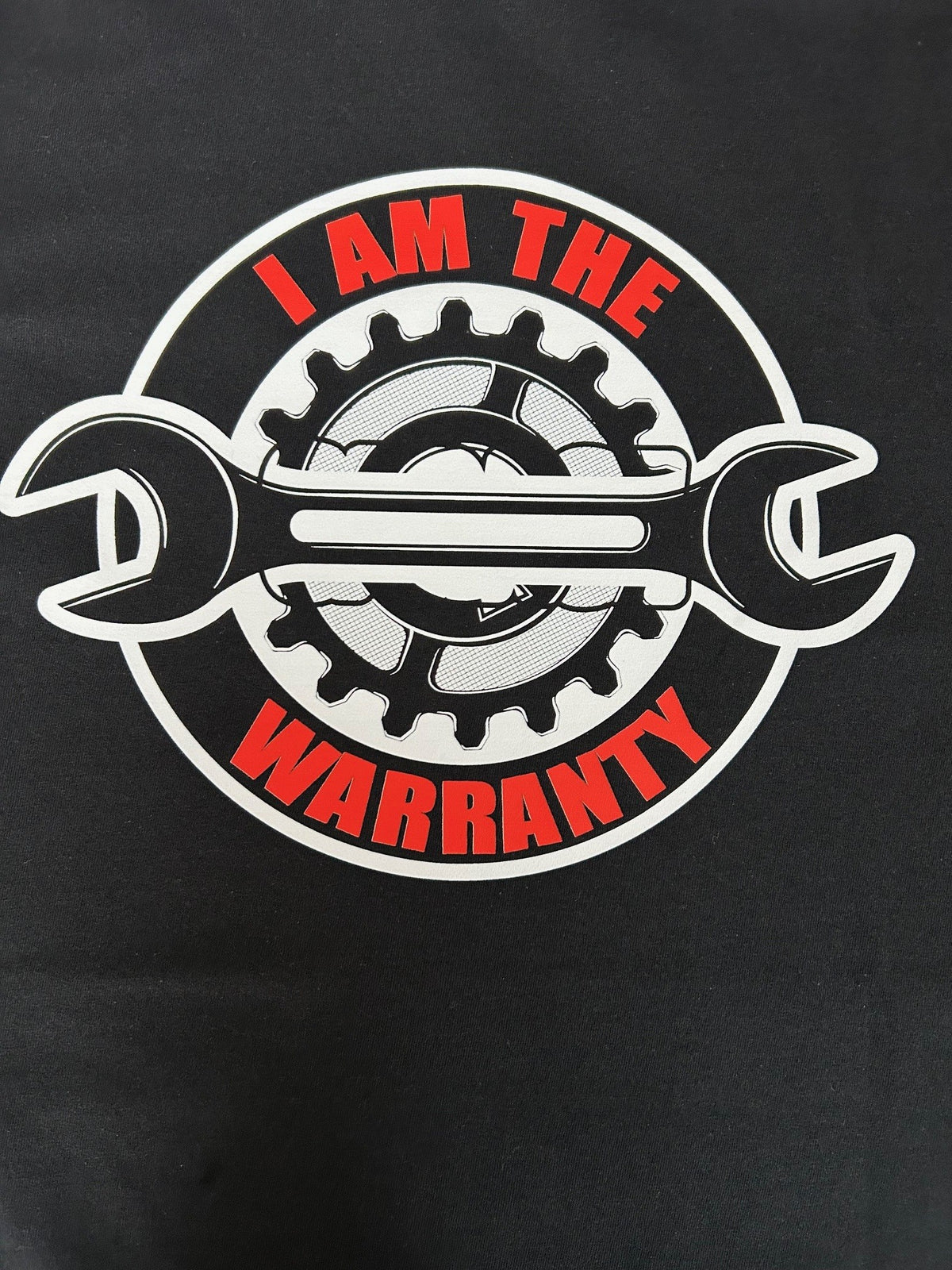 Close-up of the I Am The Warranty print on a black t-shirt