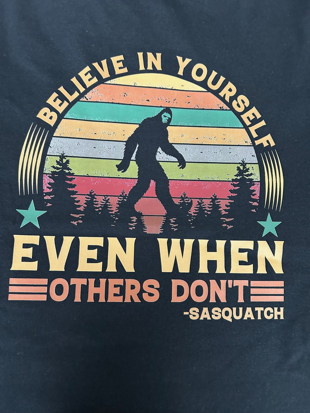 Close-up of the Believe In Yourself Sasquatch print on a black t-shirt