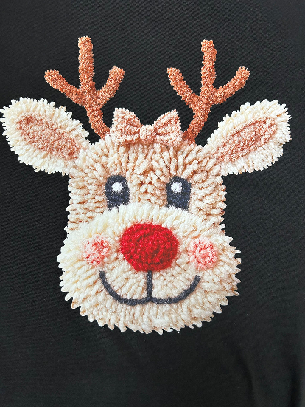 Close-up of the chenille-look reindeer face print on a black t-shirt