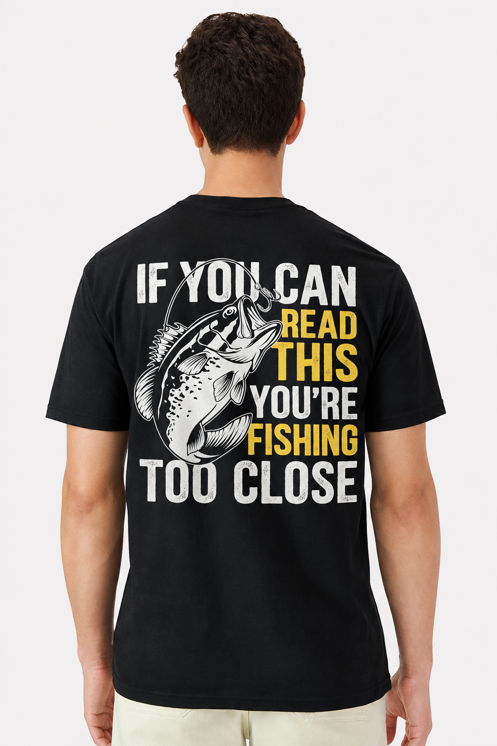 Back view of a model wearing a black t-shirt with a large If You Can Read This You're Fishing Too Close bass print