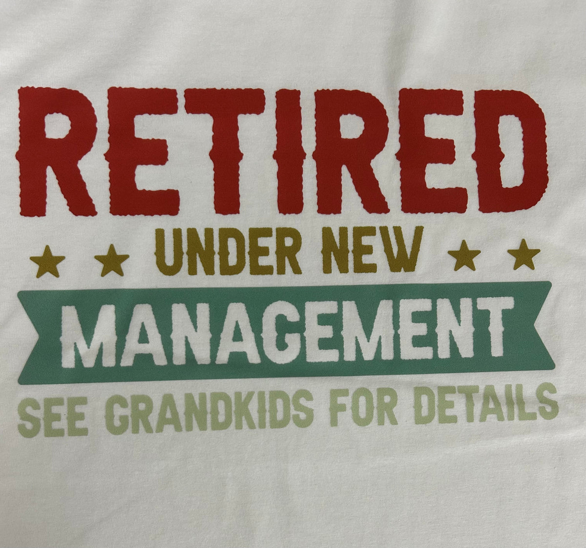 Close-up of the Retired Under New Management print on a white t-shirt