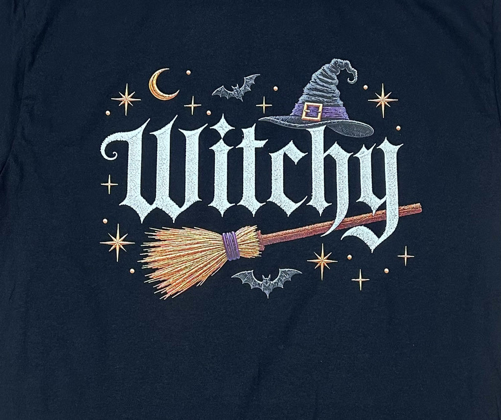 Close-up of the Witchy witch hat and broomstick print on a black t-shirt